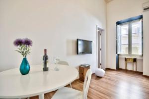 een witte eetkamer met een tafel en een vaas met paarse bloemen bij Valletta Timeless Elegance : City Centre Apartment in Valletta