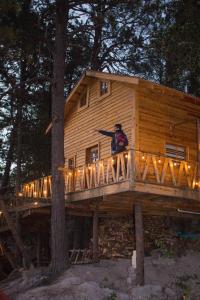 a man standing on the deck of a tree house at Wooden Inn - Cabañas Boutique y Bubble Glamping en Creel in Creel