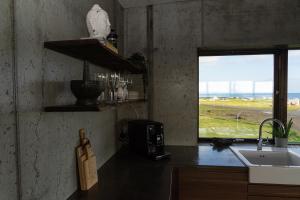 uma cozinha com um balcão com um lavatório e uma janela em Converted Water Tower em Grindavík