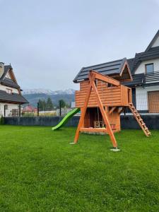 a playground with a slide in a yard at Apartamenty u Gąsieniców Zakopane in Zakopane