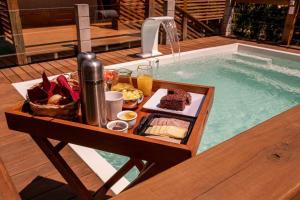 uma bandeja de comida numa mesa ao lado de uma piscina em Pousada Makani na Praia do Rosa