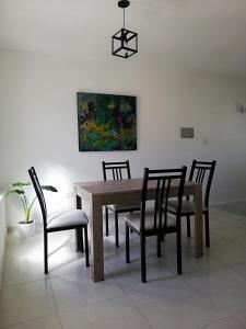 a dining room table with chairs and a painting on the wall at Disfruta como local II (dpto) in La Cieneguita