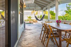 a porch with a wooden table and chairs and a hammock at Sea Foam Villa in Osbourn