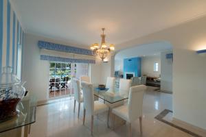 a dining room with a glass table and white chairs at Villa Wilker in Vilamoura