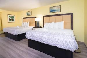 a hotel room with two beds with white sheets at Heart of Manteo in Manteo