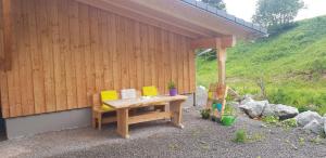 Ferienwohnung Natururlaub Muggenbrunn في تودتناو: طاولة خشبية ذات وسائد صفراء جالسة بجوار مبنى