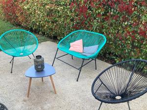 three chairs and a table and a chair with a pillow at Aux couleurs d'Ardèche in Vallon-Pont-dʼArc