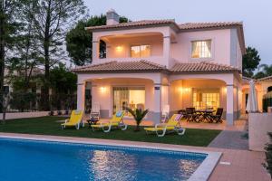 a villa with a swimming pool in front of a house at Villa Wilker in Vilamoura