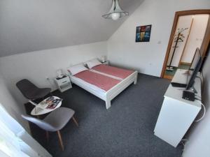 um quarto com uma cama, uma televisão e uma cadeira em Apartmani Denis em Dubrave Gornje