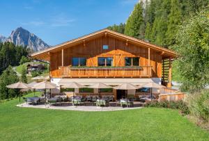 a log house with a deck with tables and umbrellas at Dolomiti Lodge Alverà in Cortina dʼAmpezzo