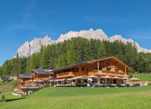un edificio en una colina con una montaña en el fondo en Dolomiti Lodge Alverà en Cortina dʼAmpezzo