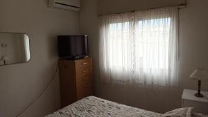 Schlafzimmer mit einem Bett, einem TV und einem Fenster in der Unterkunft Departamento 2 ambientes 1er piso in Gualeguay