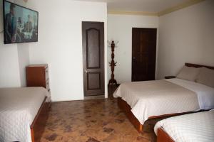 a bedroom with two twin beds and a door at Hotel Lili - Popayán in Popayan