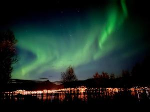 una aurora en el cielo sobre una ciudad por la noche en Håkøya Lodge, en Tromsø