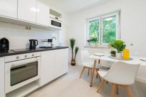 a kitchen with white appliances and a table and chairs at EG Rechts -Wunderschöne 80m² große 3-Zimmer City Wohnung nähe Salzburg in Freilassing