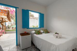um quarto com uma cama com acabamentos azuis e uma janela em Pousada Astral Mucugê em Arraial d'Ajuda