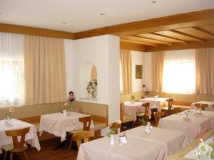 a restaurant with tables and chairs with white table cloth at Garni Kofler in Tirolo