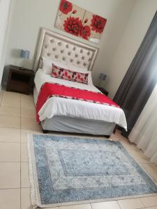 1 dormitorio con 1 cama con edredón rojo y blanco en Ikhwezi guest house en East London
