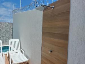 a white chair sitting on a balcony with a wooden wall at Casa Barra de São Miguel 4 quartos - BarraMar in Barra de São Miguel