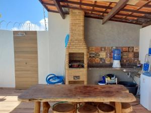 a wooden table in a kitchen with a brick oven at Casa Barra de São Miguel 4 quartos - BarraMar in Barra de São Miguel