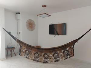 a room with a tv and a hammock on a wall at Casa Barra de São Miguel 4 quartos - BarraMar in Barra de São Miguel