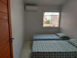 two beds in a room with a window at Casa Barra de São Miguel 4 quartos - BarraMar in Barra de São Miguel +29 photos