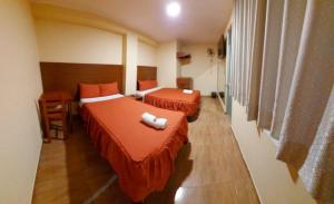 a hotel room with two beds and a desk and window at Lembranças Hotel in Huánuco