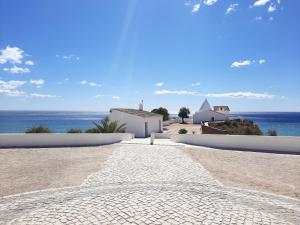 une route pavée menant à un bâtiment blanc et à l'océan dans l'établissement Gui Beach House, à Armação de Pêra