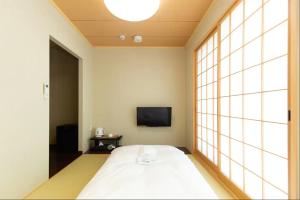 um quarto com uma cama grande e uma televisão em Karasuma Rokujo Hotel em Quioto