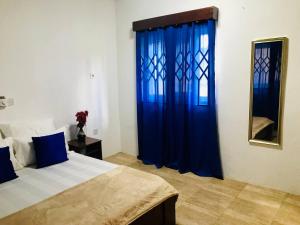 a bedroom with a bed with blue curtains and a mirror at Moroccan Tile House - Tranquil Estate - Boundary Rd in Madina