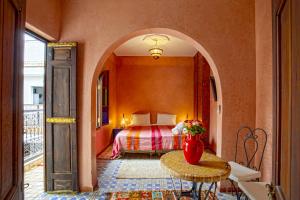 a bedroom with a bed and a table with a vase on it at Riad Lakhdar in Marrakesh