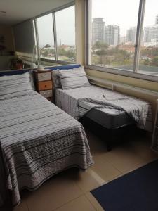 twee bedden in een kamer met een groot raam bij Apartamento en Edificio Vanguardia in Punta del Este