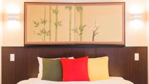 a painting above a bed with colorful pillows at Kyoto Inn Gion The Second in Kyoto