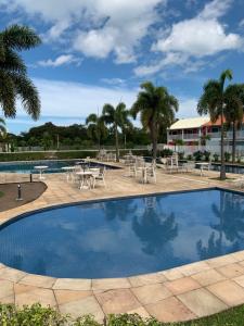 ein Pool mit Tischen und Stühlen und Palmen in der Unterkunft Melhor casa Praia na Reserva do Sahy in Mangaratiba