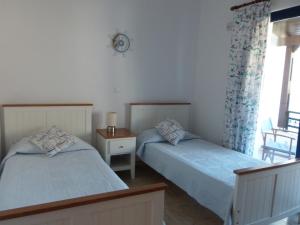 a bedroom with two beds and a table and a window at Pebble in Pefki