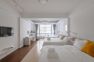 ein weißes Wohnzimmer mit 2 Betten und einem TV in der Unterkunft 藍色知更鳥旅宿 in Hualien