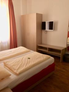 a bedroom with a bed with a tv on the wall at Gasthof Bären in Ochsenfurt