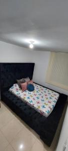 a bed with a black bed frame in a room at Arturo Apartamento Con hermosa vista y piscina in Armenia +2 photos