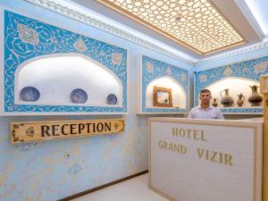 a man standing behind a sign in a room with blue walls at Grand Vizir Hotel in Khiva