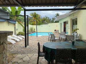 a patio with a table and chairs and a pool at Villa 'Les Cocotiers' proche du lagon de la Saline in La Saline les Bains