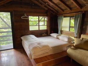 een groot bed in een houten kamer met ramen bij lai Home Country Cottage B&B in Meishan