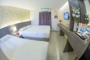 a hotel room with two beds and flowers in it at Hotel SIN JO in Johor Bahru