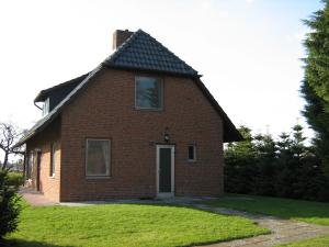 een rood bakstenen huis met een zwart dak bij Ferienhaus Küste in Otterndorf