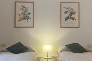 two beds in a room with two pictures on the wall at Bronzino Flexyrent Renewed - AC - WiFi in Florence +13 photos
