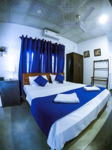 a bedroom with a large bed with blue sheets and pillows at Mirissa Blue Whale Holiday Hotel in Mirissa