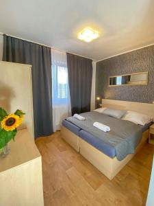 a bedroom with a bed and a vase with a sunflower at Penzion Hustopeče in Hustopeče