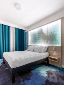 a bedroom with a large bed with blue curtains at ibis Styles Dunarea Galati in Galaţi