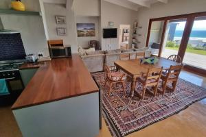 a living room with a table and a couch at Hilltop Heaven, Walk to beach, Pool, Ocean & River views in Pringle Bay