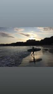 una persona caminando por la playa con una tabla de surf en TOMI in Shimoda, en Shimoda