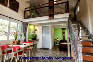 een woonkamer met een trap en een tafel en stoelen bij Phayam Friends in Ko Phayam